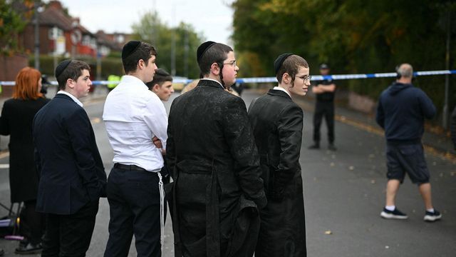 2025년 10월 2일, 맨체스터 북부 크럼솔에 위치한 히튼 파크 유대교 회당 인근에서 지역 주민들이 경찰 차단선 근처에 서 있는 모습