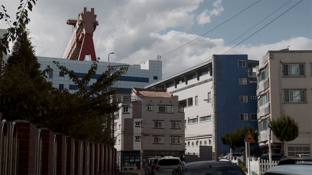 여러 채의 빌라 건물 뒤로 크레인이 보이는 사진 