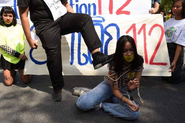 밧줄에 묶인 채 바닥에 쓰러진 여성을 발로 차는 듯한 시늉을 하는 남성의 모습
