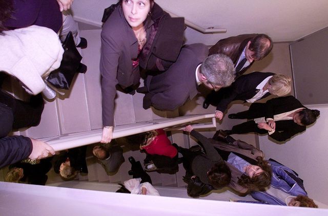 사람들이 한 줄로 계단을 내려가고 있다. 한 사람은 시계로 시간을 재고 있다.