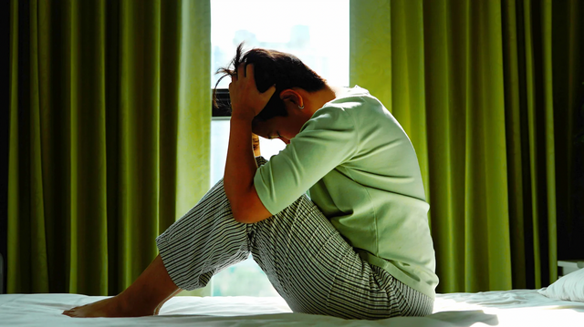 침대 위에서 머리를 감싸 안으며 고민을 하고 있다. 