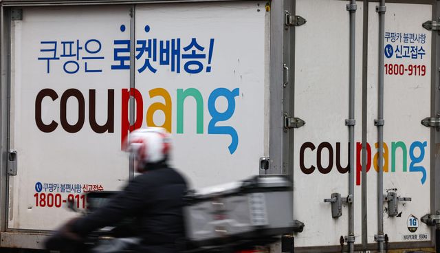 쿠팡 배송트럭과 그 앞을 지나가는 오토바이 기사