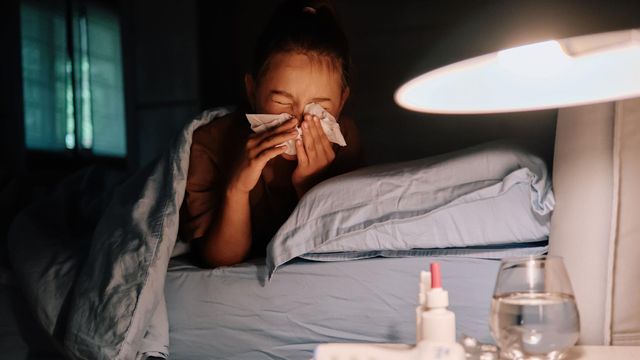 침대에 누워 코를 풀고 있는 사람의 모습