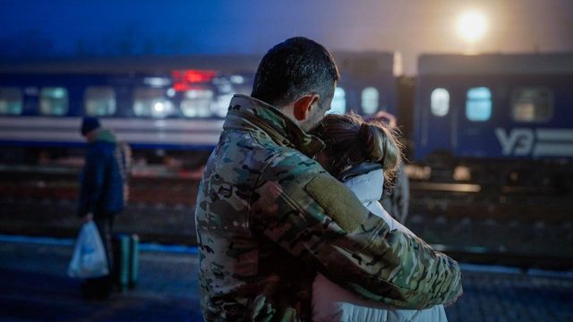 군복을 입은 남성이 열차 출발 전 한 여성을 안아주고 있다