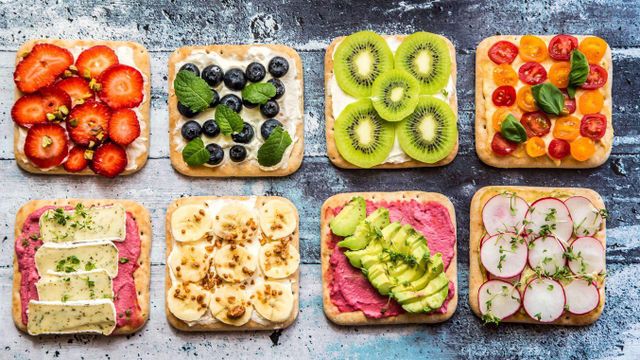 딸기, 블루베리, 아보카도, 치즈 등 다양한 재료가 얹힌 빵 조각들이 두 줄로 배열되어 있다