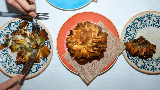 접시 위에 음식이 놓여 있고, 한 사람이 포크와 나이프를 사용하고 있다.