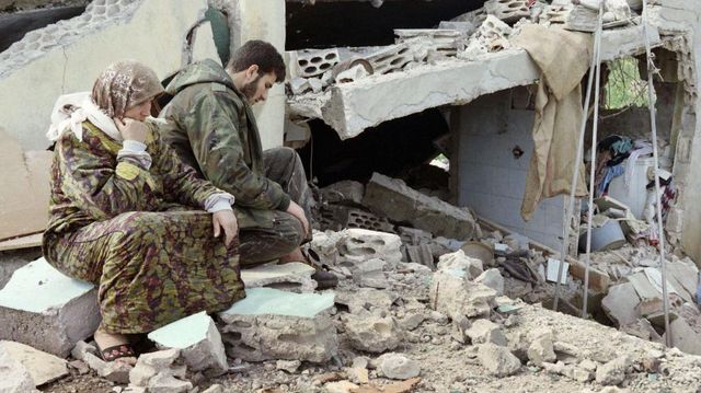 1996년 4월 28일 레바논 남부 시디키네에서 헤즈볼라 전사 한 명이 어머니와 함께 파괴된 집 옆에 앉아 있는 모습