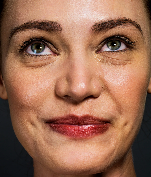 한 여성이 눈물을 흘리면서도 입은 웃고 있다 