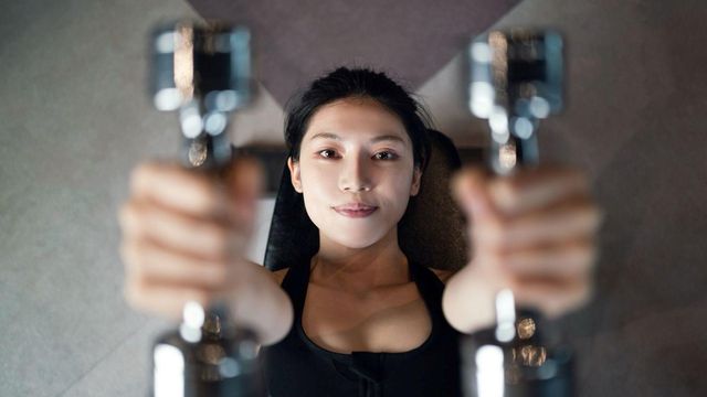 누워서 덤벨을 들고 있는 여성