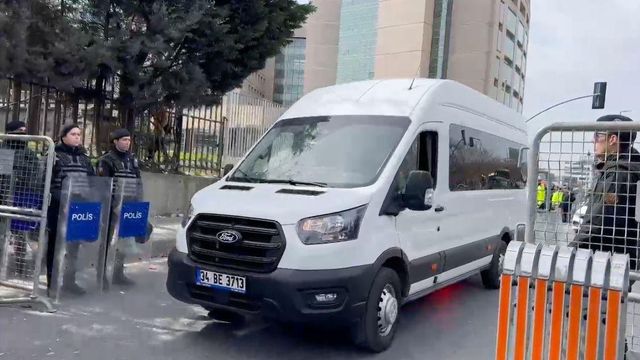 진압 경찰이 지키고 있는 거리를 지나는 차량의 모습