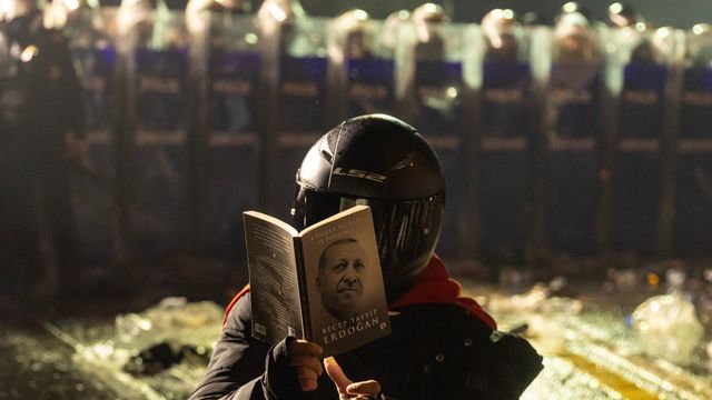 지난 23일 한 시위대가 헬멧을 쓴 채 에르도안의 책을 얼굴 앞에 들고 있는 모습