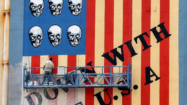 2025년 4월 8일 테헤란 카림 칸 잔드 거리의 한 건물 외벽에 그려진 반미 상징 벽화에 한 남성이 새 페인트를 덧칠하고 있다. 이 벽화에는 "미국을 타도하자"는 구호와 함께 성조기의 별 대신 해골이 그려져 있다