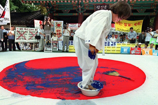 2001년 7월 9일 서울에서 열린 반일 시위에서 한 한국 활동가가 논란이 되고 있는 일본의 역사 교과서 수정 거부에 항의하며 일본 국기를 파란색 페인트로 칠하고 있다