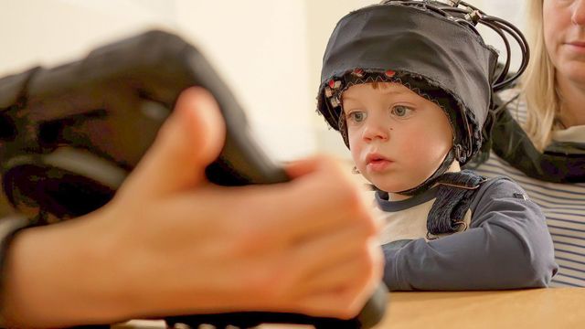 머리에 실험 장치를 쓰고 화면을 바라보고 있는 2세 아동