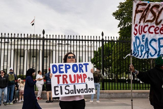 백악관 앞에서 “트럼프를 엘살바도르로 추방하라”라고 적힌 팻말을 든 여성