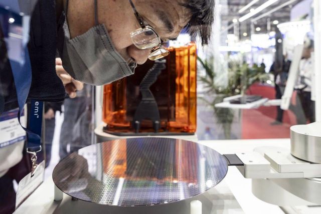 박람회에서 원형 반도체 웨이퍼를 바라보고 있는 남성의 모습