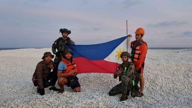 모래언덕에서 자국 국기를 펼쳐 든 필리핀 대원들의 모습