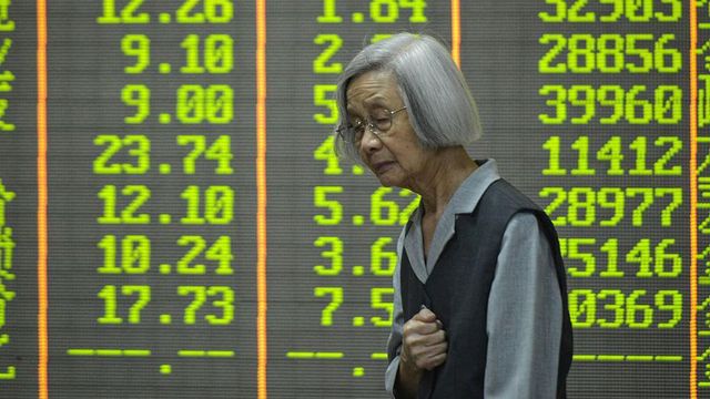 중국 동부 저장성 소재 한 증권회사의 스크린 앞에서 오른손을 가슴 가까이 대고 있는 나이 든 여성의 모습