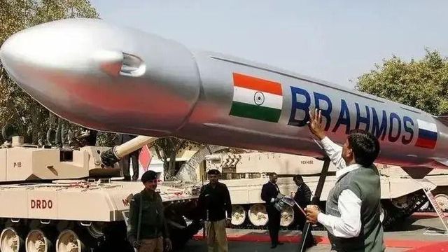 브라모스 순항미사일에 손을 올린 남성과 뒷 배경에 보이는 탱크