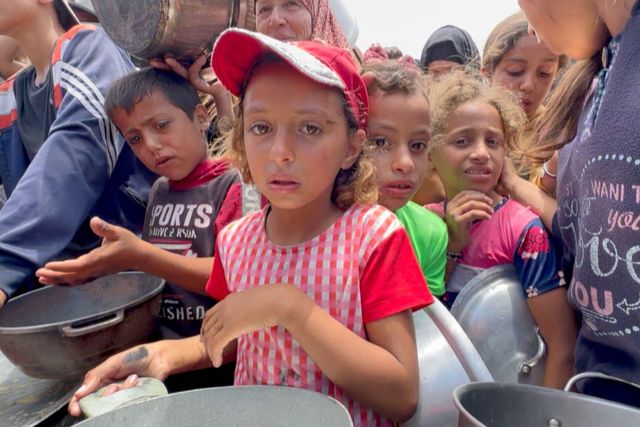 빈 그릇을 들고 줄을 서서 배식을 기다리는 어린아이들의 모습