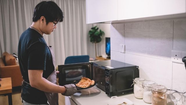 전자레인지에서 피자 한 조각을 꺼내는 남성의 모습