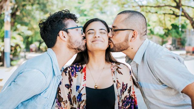 두 남성으로부터 볼에 입맞춤을 받는 여성의 모습