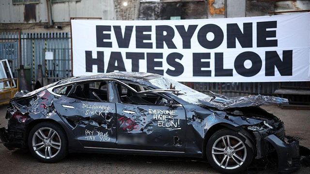 망가진 테슬라 뒤에 "모두가 일론을 미워한다"고 적힌 현수막