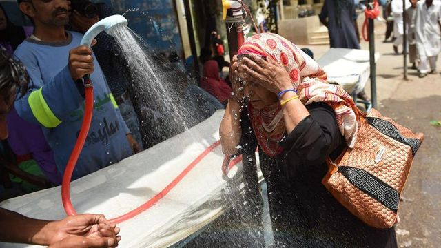머리에 히잡을 두른 여성이 물로 열기를 식히고 있다