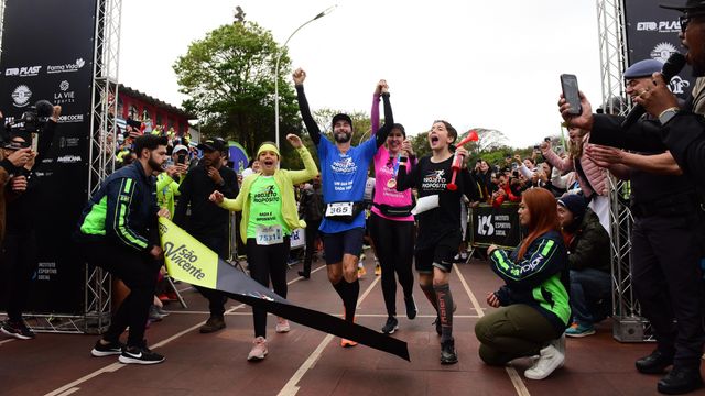 파리아스는 양옆 사람들과 손을 맞잡은 채 결승선을 통과하며 달리고 있다.