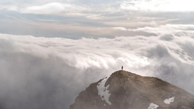 산 정상에서 구름을 바라보고 있는 사람