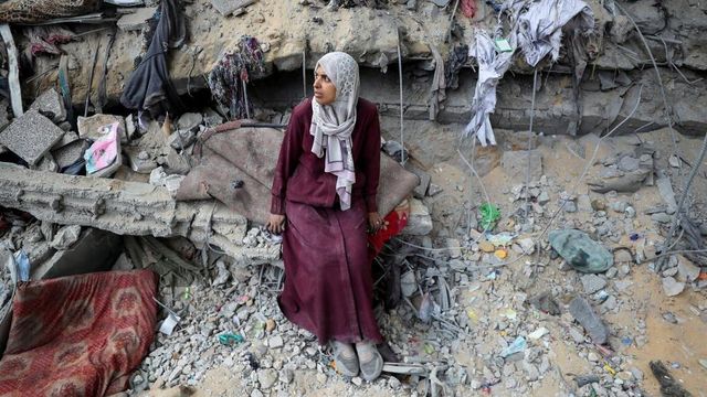 가자 지구의 건물 잔해 속에 서 있는 팔레스타인 여성