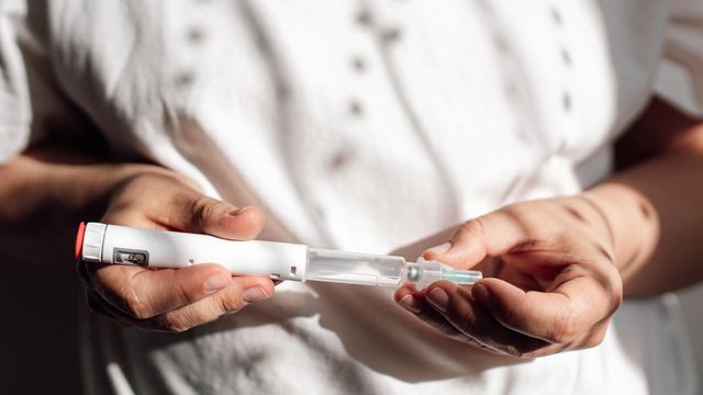 흰색 주사기펜을 들고 있는 여성의 모습