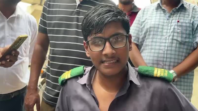 교복 차림의 파르한 하산이 어른들에 둘러싸여 카메라를 응시하는 모습