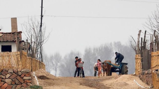 2017년 4월 16일 북한 신의주 압록강변 도로에서 한 북한 남성과 여러 명의 어린이들이 자전거를 타며 노는 모 습 