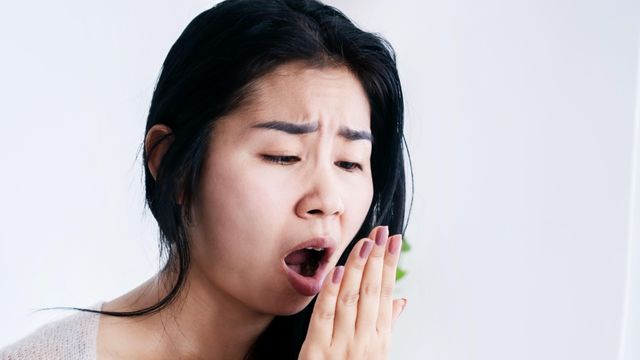 한 여성이 자신의 입 냄새를 확인하려고 손을 입 앞에 대고 숨을 내쉰다