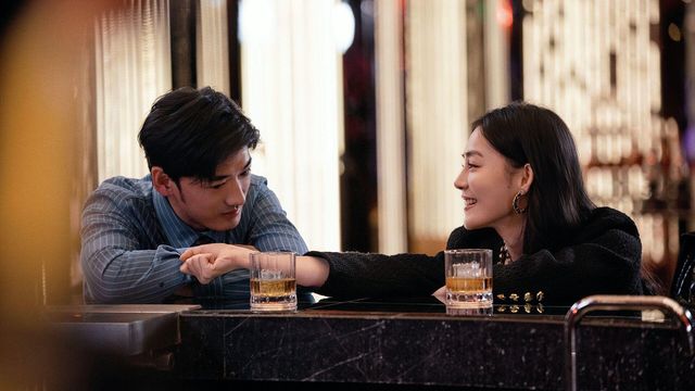 비디오 게임 ‘감정적 반(反)사기 시뮬레이터(Emotional Anti-Fraud Simulator)’의 한 장면에는 바에 앉아 대화를 나누는 남녀가 등장한다. 탁자 위에는 술잔 두 개가 놓여 있고, 남성은 파란색 긴팔 셔츠를, 여성은 검은색 가디건과 금색 귀걸이를 착용하고 있다.