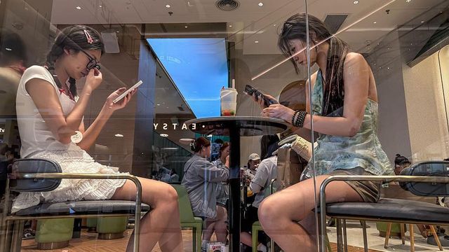 중국 충칭의 한 찻집에서 두 젊은 여성이 마주 앉아 각자 스마트폰을 하고 있다.