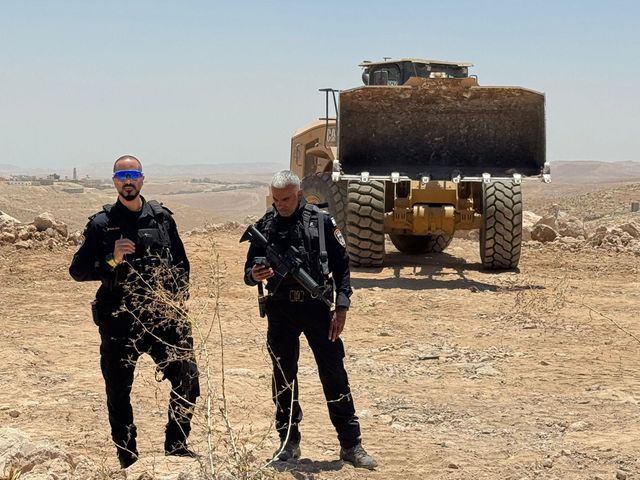 굴착기 주변에서 경계 근무를 서고 있는 남성들의 모습