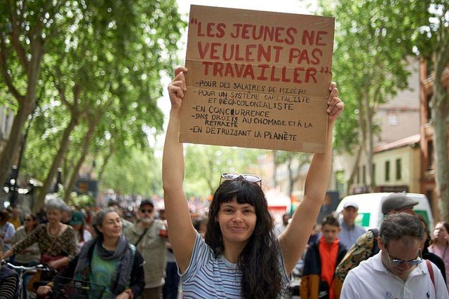 '청년들은 실업 보험과 연금 혜택도 없이 형편없는 임금을 받으며 지구를 파괴하는 자본주의 및 신식민지 체제를 위해 일하고 싶지 않다'고 적힌 플래카드를 들고 있는 젊은 여성의 모습