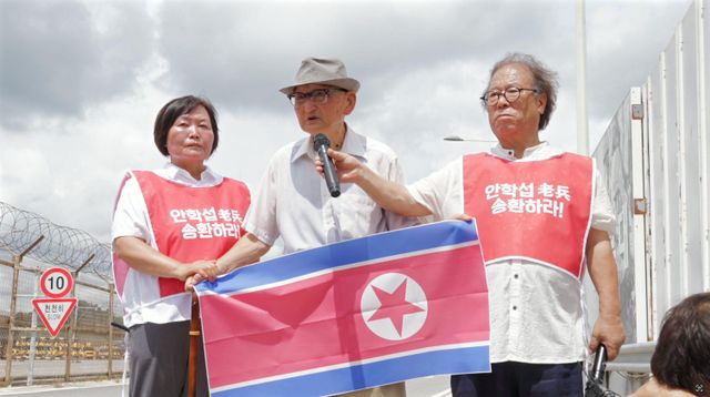 북한 인공기를 들고 통일대교에 서 있는 안학섭 씨와 안학섭선생송환추진단