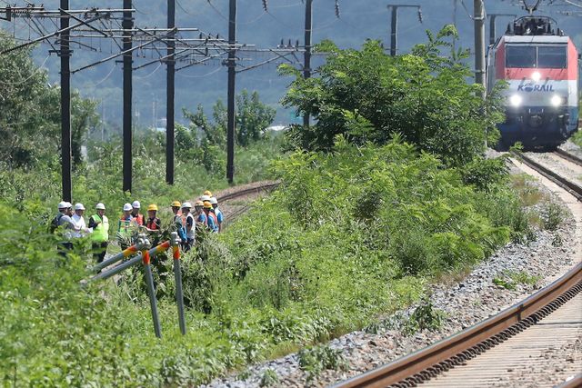 경찰과 소방, 코레일 등 관계자들이 사고 현장을 조사하는 가운데 우측으로 열차가 서행하고 있다