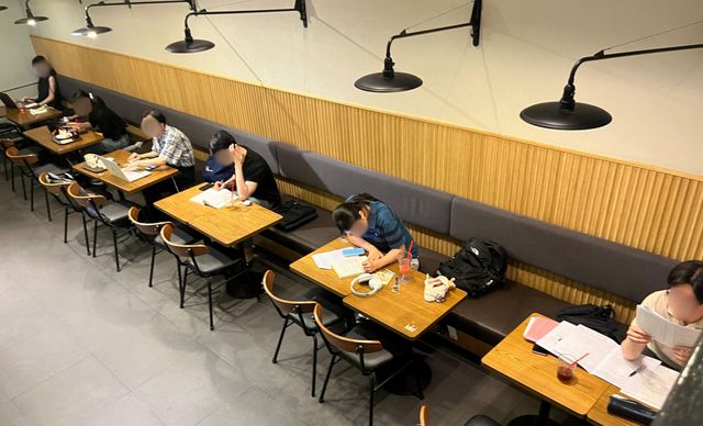 한 프랜차이즈 커피 체인점에 사람들이 각자 책상에 앉아 공부나 일을 하고 있다