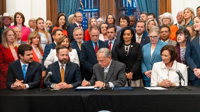 주 정부 관계자들 가운데 그레그 애벗 텍사스 주지사가 법안에 서명하는 모습