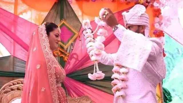 수니타 C와 그녀의 남편 중 한 명인 프라딥 N이 결혼식에서 화환을 교환하고 있다