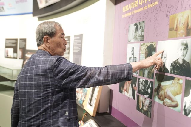 피폭자들의 당시 피해 사진을 보여주고 있는 심진태 씨