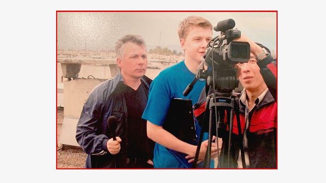 젊은 파벨 자루빈을 포함한 세 명의 영화 제작진이 비디오 카메라 옆에 서 있다. 자루빈은 파란색 티셔츠를 입고 비디오 카메라의 뷰파인더를 들여다보고 있다. 빨간색 재킷을 입은 한 남성이 카메라 상단을 만지고 있다. 그들은 도시 스카이라인을 뒤로 하고 야외에 서 있다