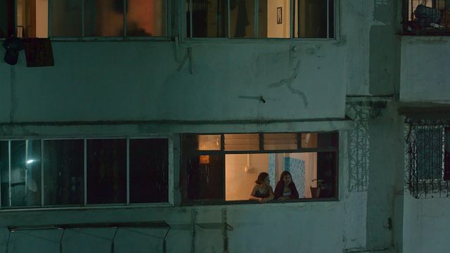 두 여성이 오래된 아파트 창문에서 이야기를 나누고 있다