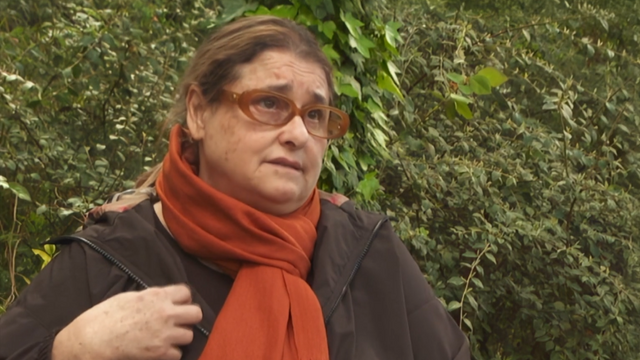 갈색 안경에 갈색 코트, 주황색 스카프를 두른 여성