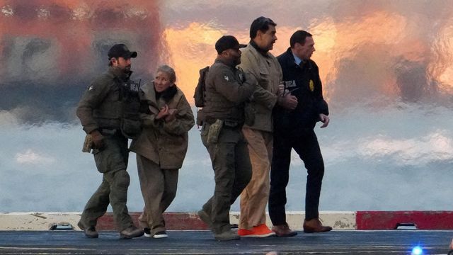 뉴욕시 활주로에서 세 명의 미국 사법당국 요원들이 수갑이 채워진 니콜라스 마두로 대통령과 그의 부인 실리아 플로레스 여사를 호송하고 있다. 