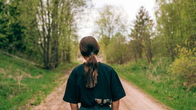 흙길 위에 등을 돌린 채 서 있는 미성년자.